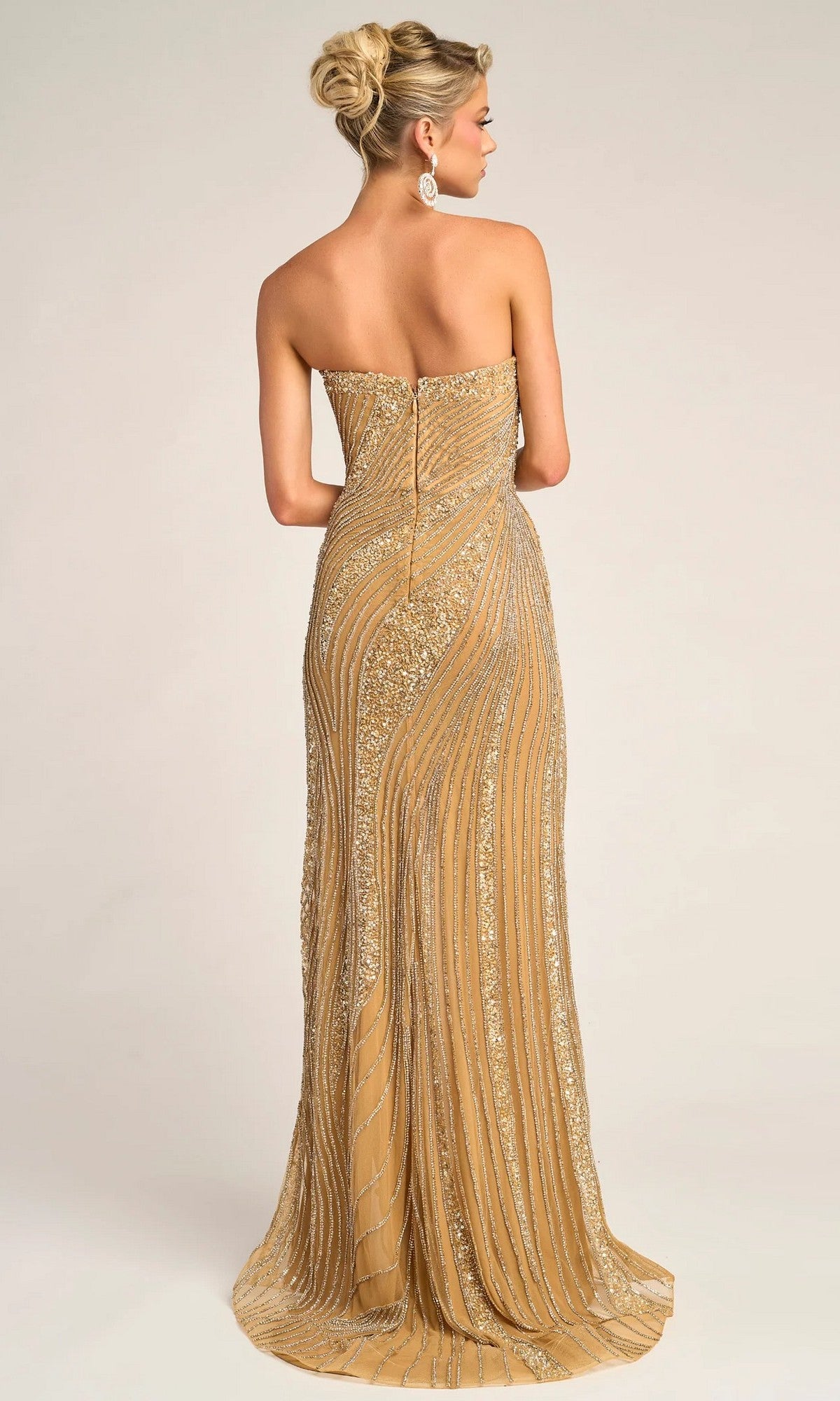 A woman faces away, wearing the Portia and Scarlett PS26410C long formal dress in gold with sparkling beaded embellishments, her hair styled in an elegant updo.